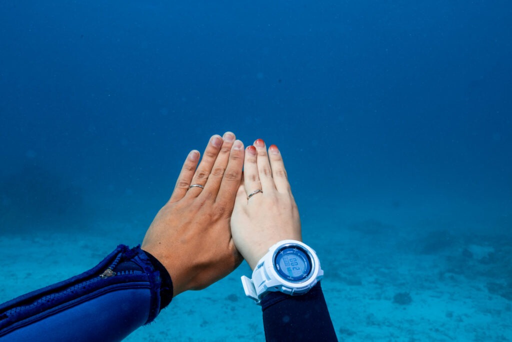 沖縄の海中で重ねた手と結婚指輪